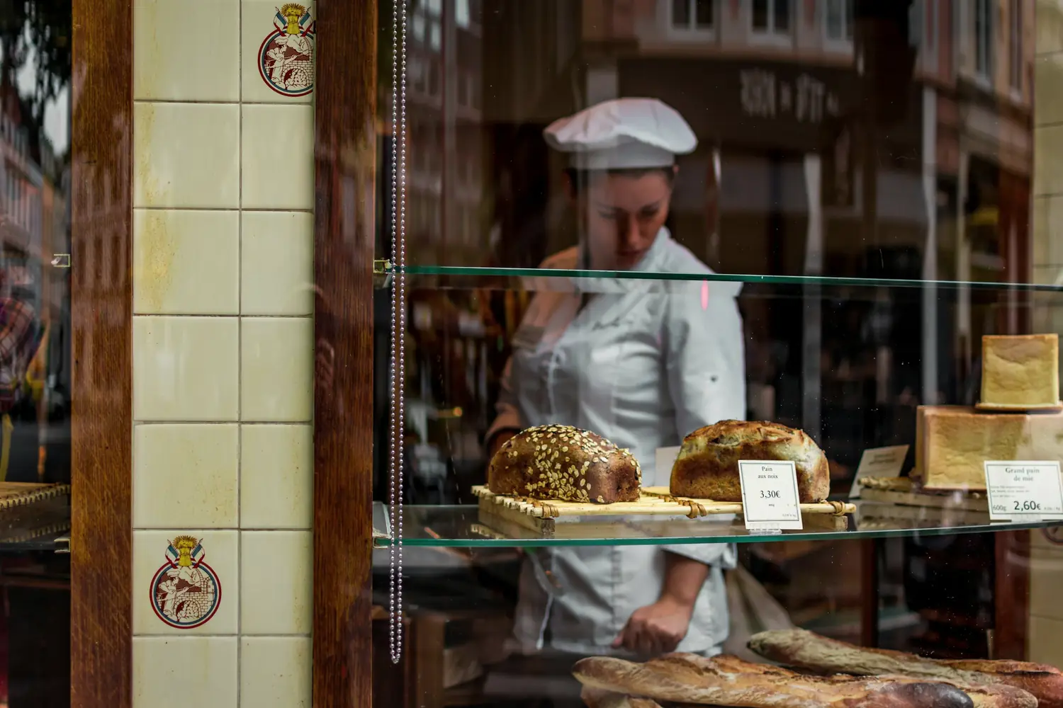 A baker arranging bread behind a shop window