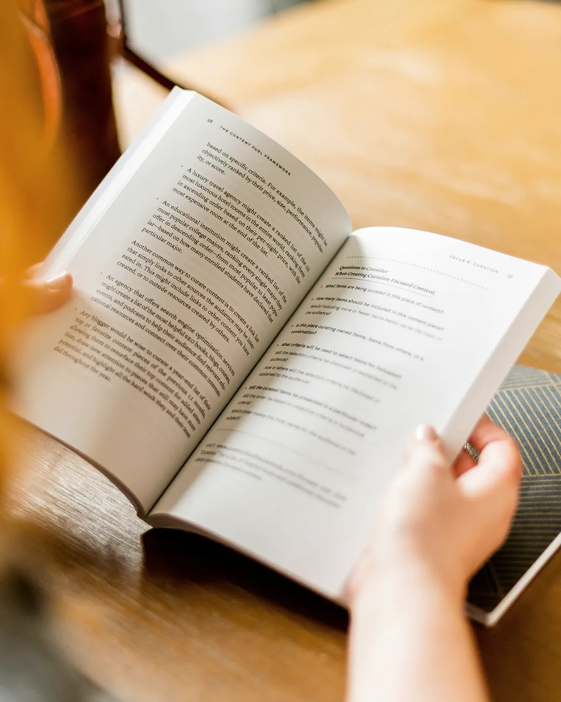 A person taking notes beside open books in daylight