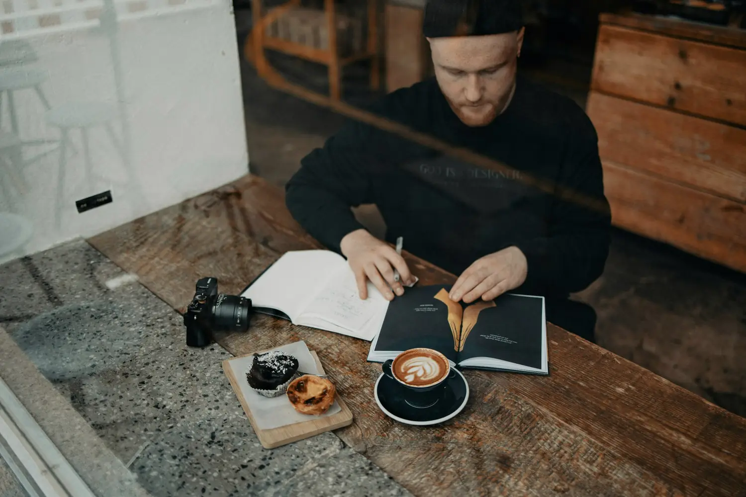 A man writing in a notebook at a café table